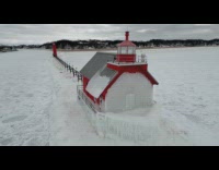 Drone shot of icy lighthouse in lake