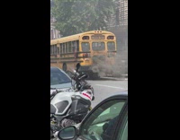 School bus parked on street with black smoke coming of exhaust pipe