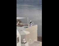 Woman on white robe pictures wine glass on balcony