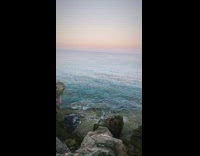View blue ocean water rocks pink sunset  