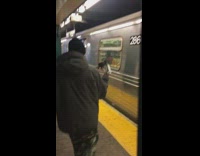 Guy holds trash in his hands while walking in subway station