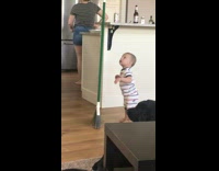 Baby balances green broom and makes it balance