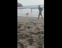 Man poses on the beach with a woman takes his picture