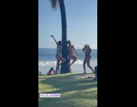 Two women in a bikini poses beside the tree
