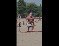 Man does squat with lady on his shoulders at park beach 