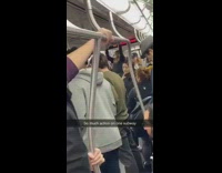 Woman shaves back of guys head while subway dancer performs on other end of train