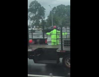 Employee in neon green holds onto side of cargo truck 