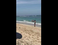 Woman jumps in sand in front of beach for a picture