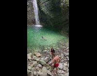 Guy red shorts film girl at waterfalls