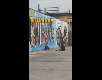 Girl blue jumpsuit sit ground wall graffiti