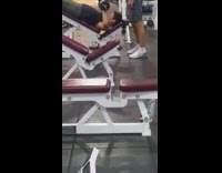 Guy on red incline bench at gym benching with free weights