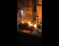 Large street fire next to red jeep at night