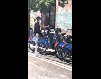 Woman pedals backwards on citibike along the street