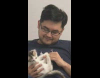 Guy holds white kitten black office chair 