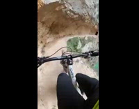 Guy rides bicycle through narrow mountain trail 