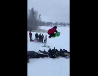 Guy on green sled jumps over friends 