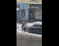 Girl uses shovel to remove snow car 