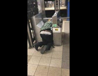 Drunk guy kneeling on floor at subway turnstile