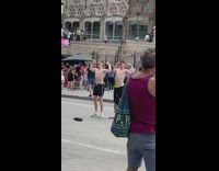 Two shirtless men flexes muscles in front of cathedral