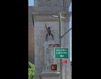 Man climbs and sits on top of statue 