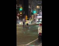 Man pushes mattress on cart at street