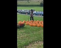 Woman in checkered top poses in front of pumpkins