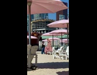Model Poses in Pink Dress next to Pink Beach Umbrellas 