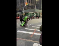 Man on atv doing wheelies on intersection 