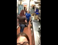 Girl in restaurant kitchen recording herself and coworkers