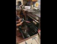 Woman pulls penis cake out of oven, glass baking pan dish slides off metal grid and falls on the floor