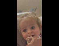 Little baby with binky in mouth says that she wants a strawberry