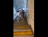 Couple carries child on both arms up stairs 