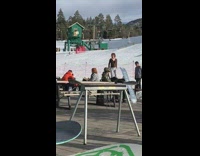 woman jumps for picture next to snow slopes
