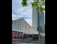 Shirtless guy tanning on lawn chair outside building