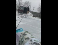 Guy rides a sled being dragged around by an SUV on icy road