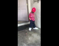 Little girl with drawn on beard wears baggy clothes, big shoes, and gold chain, pretends to be a man