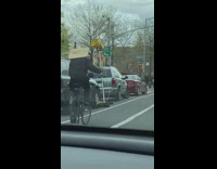 Guy on Bicycle Holds Megaphone Speaker and Sign while Riding 