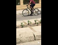 Guy riding bicycle hits curb and falls