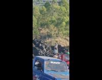 Woman lowers pants to pose with her black underwear at the rocks