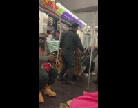 Guy pushes wooden piano on rolling cart onto subway train