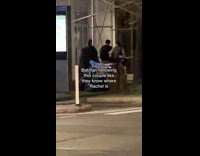 Man in batman costume follows a couple on the sidewalk