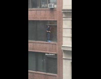 Guy face mask cleans window with squeegee 