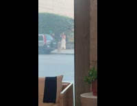 Woman in white dress with pink flowers on the sidewalk