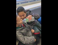 Boy feeds little brother water, squeezes water bottle and splashes his face