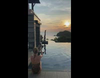 Woman black onesie headstand on poolside sunset