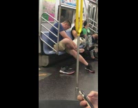 Man takes of shoes brushes and wipes bottom of feet on subway train