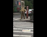 Gold statue guy walks sidewalk crosses street 