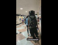 Guy walks through Airport Wearing a TV on his head
