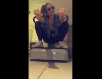 Girl squats on vibrating exercise machine, puts fists out to Gasolina