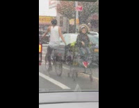 Biker pulls shopping cart with toddler in it on street 
